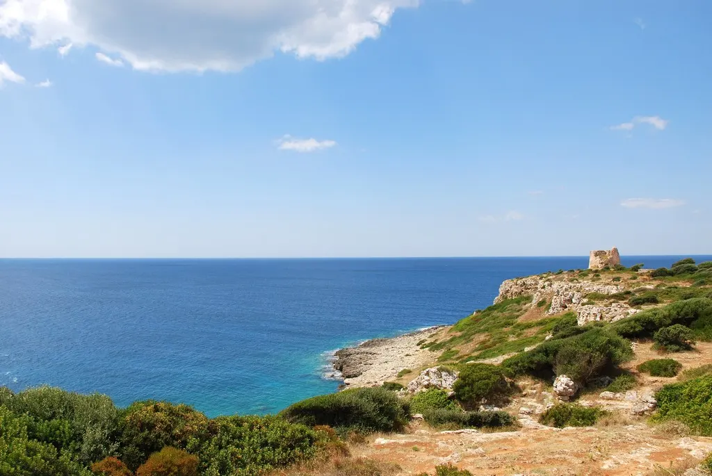 La costa rocciosa della baia con i resti di Torre Uluzzo sul promontorio.