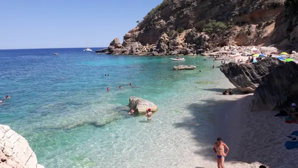 Scorcio della spiaggia di Cala Mariolu con ciottoli, rocce e acqua trasparente.