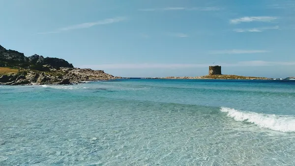 Acqua bassa della spiaggia La Pelosa con la torre sullo sfondo.