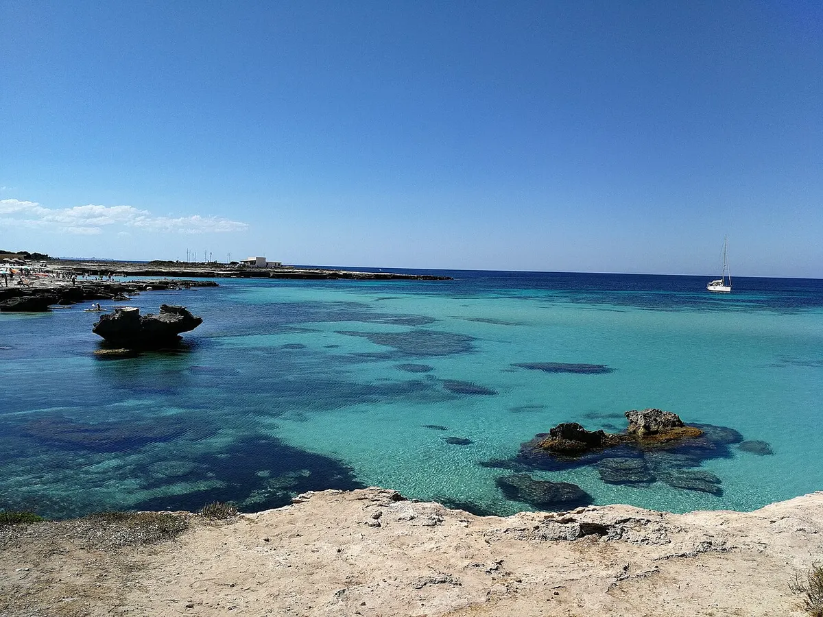 Acqua e scogli piatti presso Lido Burrone a Favignana; il margine roccioso non mostra tutta la spiaggia sabbiosa.
