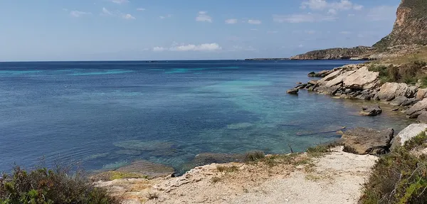 Rocce e mare nella parte rocciosa di Cala Marasolo a Favignana, con la costa sullo sfondo.