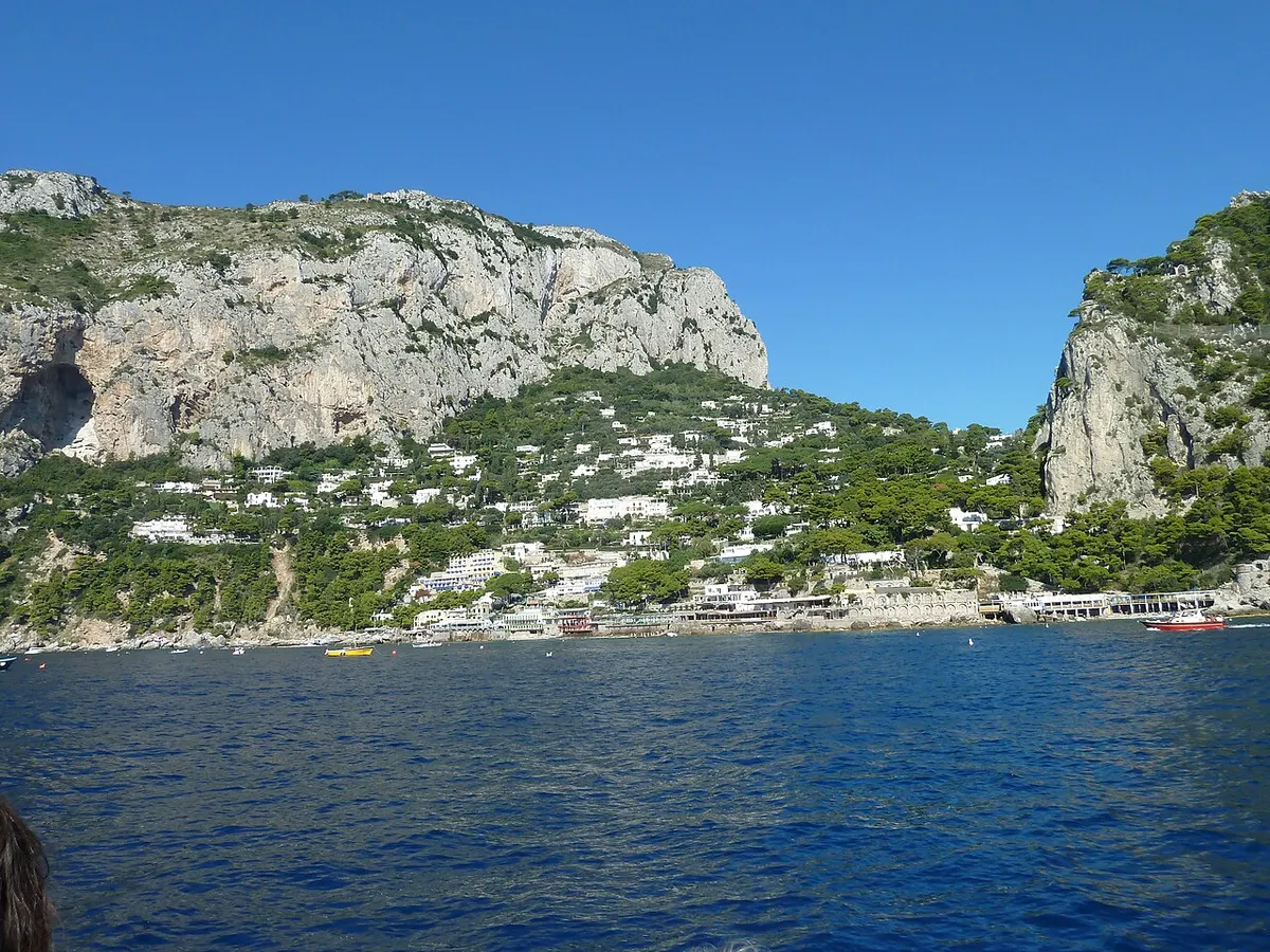 Panorama dal mare della baia di Marina Piccola a Capri, con edifici e falesie sullo sfondo.