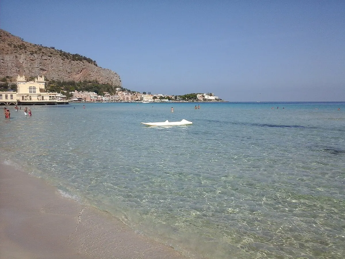 Riva della spiaggia di Mondello, con il mare e gli edifici lungo la costa.