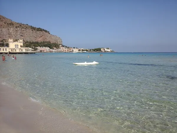 Riva della spiaggia di Mondello, con il mare e gli edifici lungo la costa.